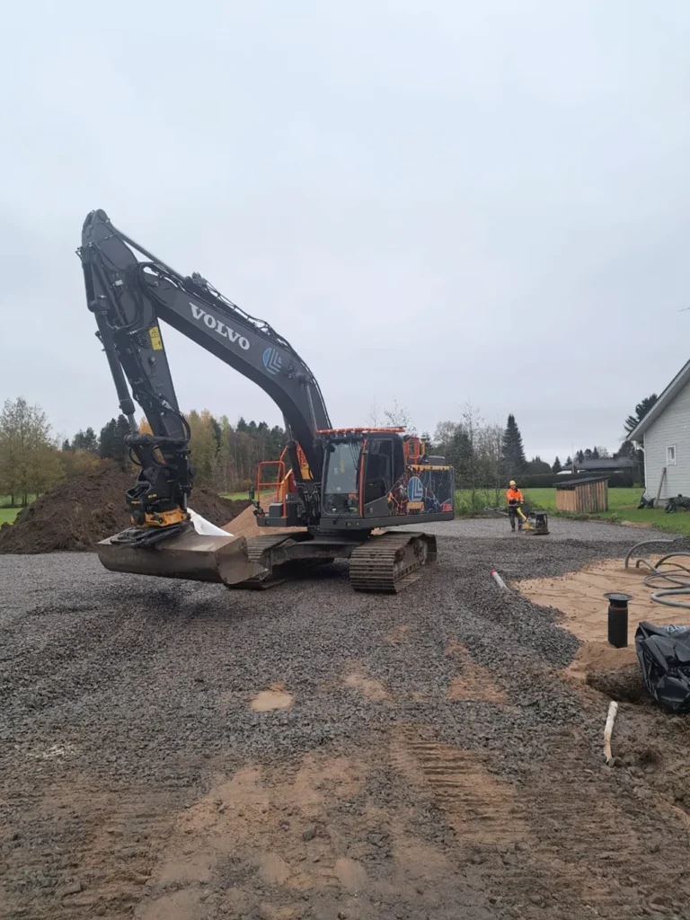 Kaivinkone levittää mursketta omakotitalon pihalle